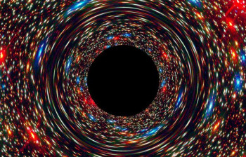 This computer-simulated image shows a supermassive black hole at the core of a galaxy. The black region in the center represents the black hole's event horizon, where no light can escape the massive object's gravitational grip. The black hole's powerful g